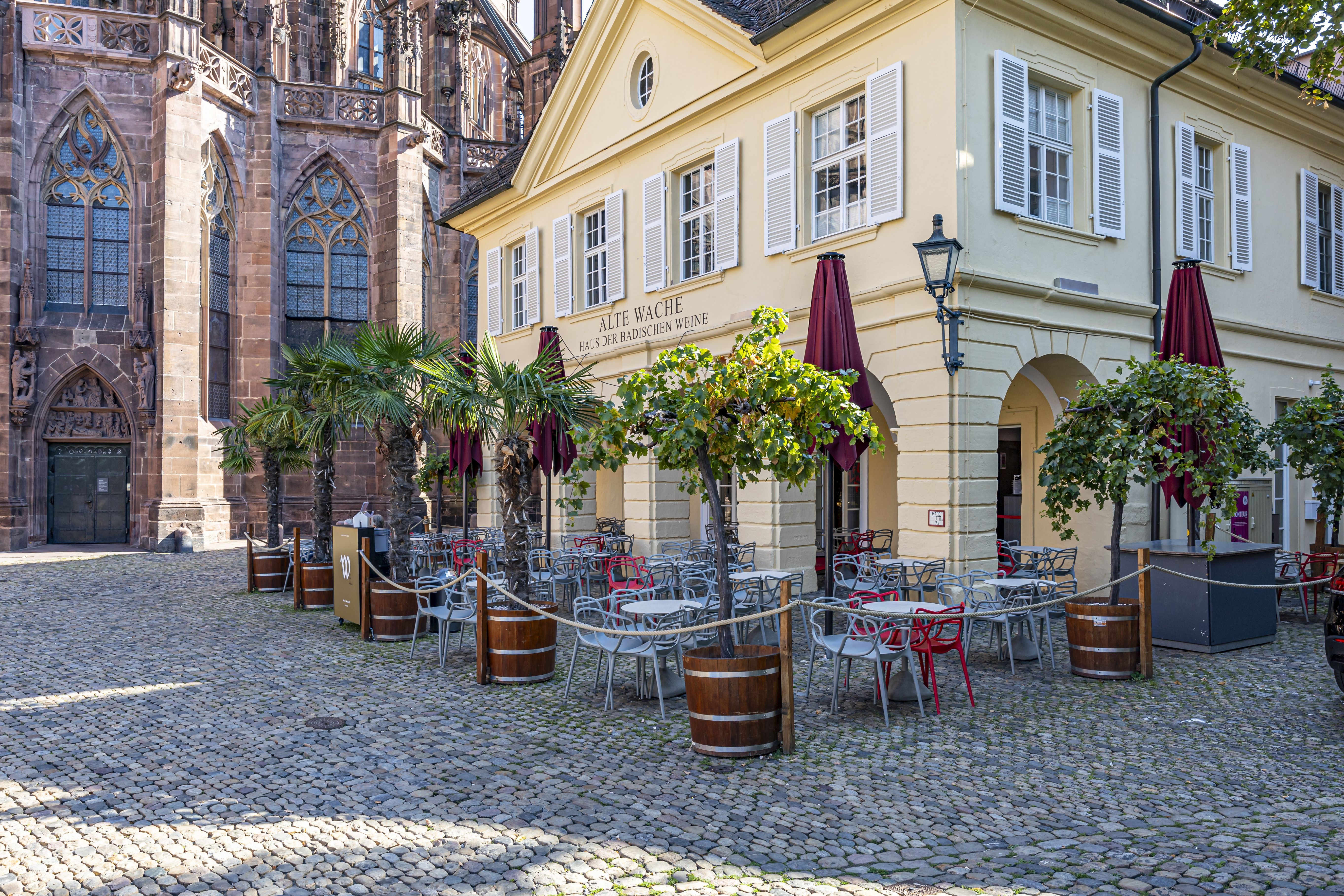 Außenansicht und Sitzbereich Alte Wache - Haus der badischen Weine mit Münster im Hintergrund