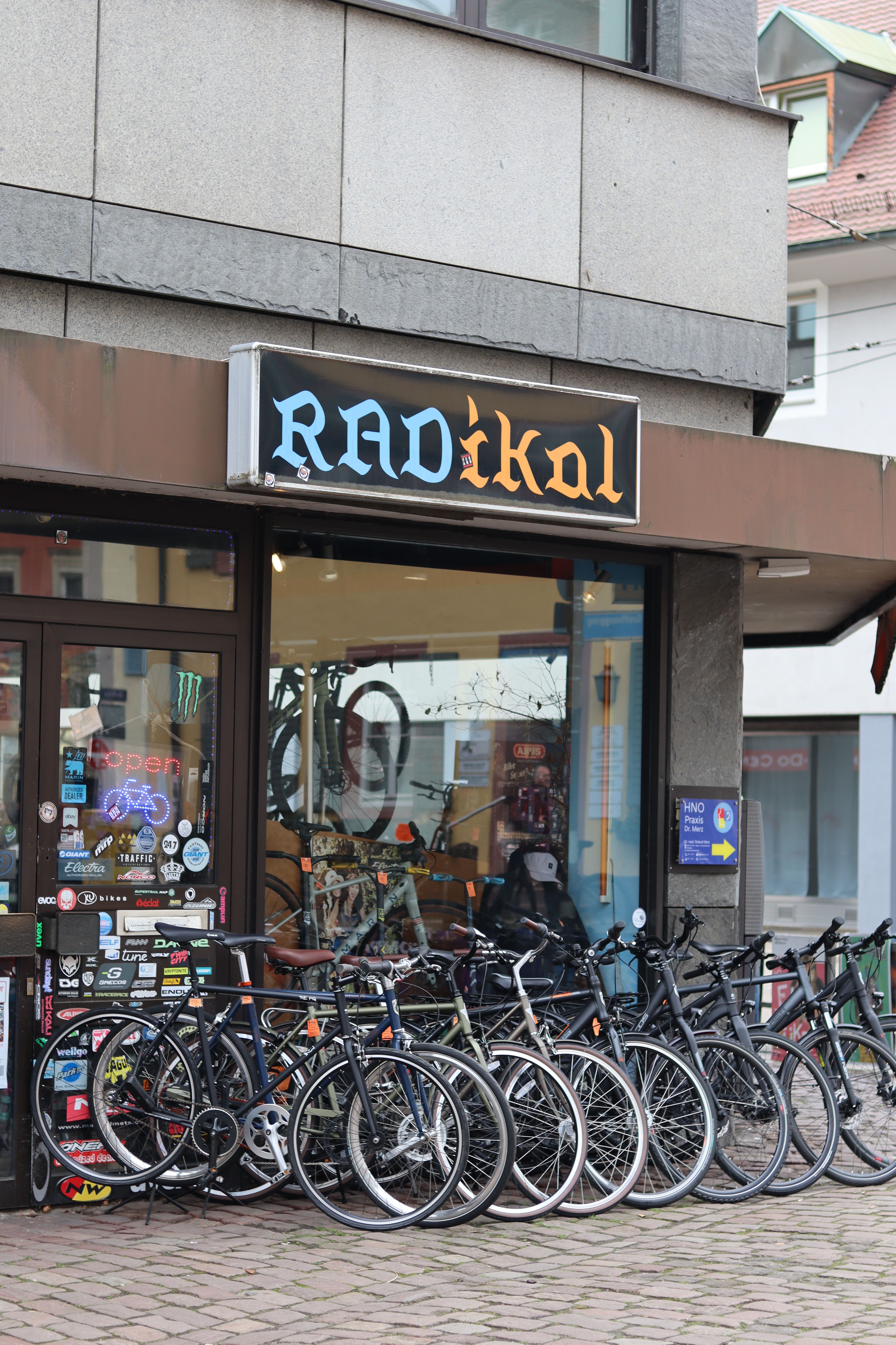 Fahrradgeschäft 'RADikal' mit mehreren Fahrrädern vor dem Eingang. Das Schaufenster ist mit Aufklebern dekoriert.