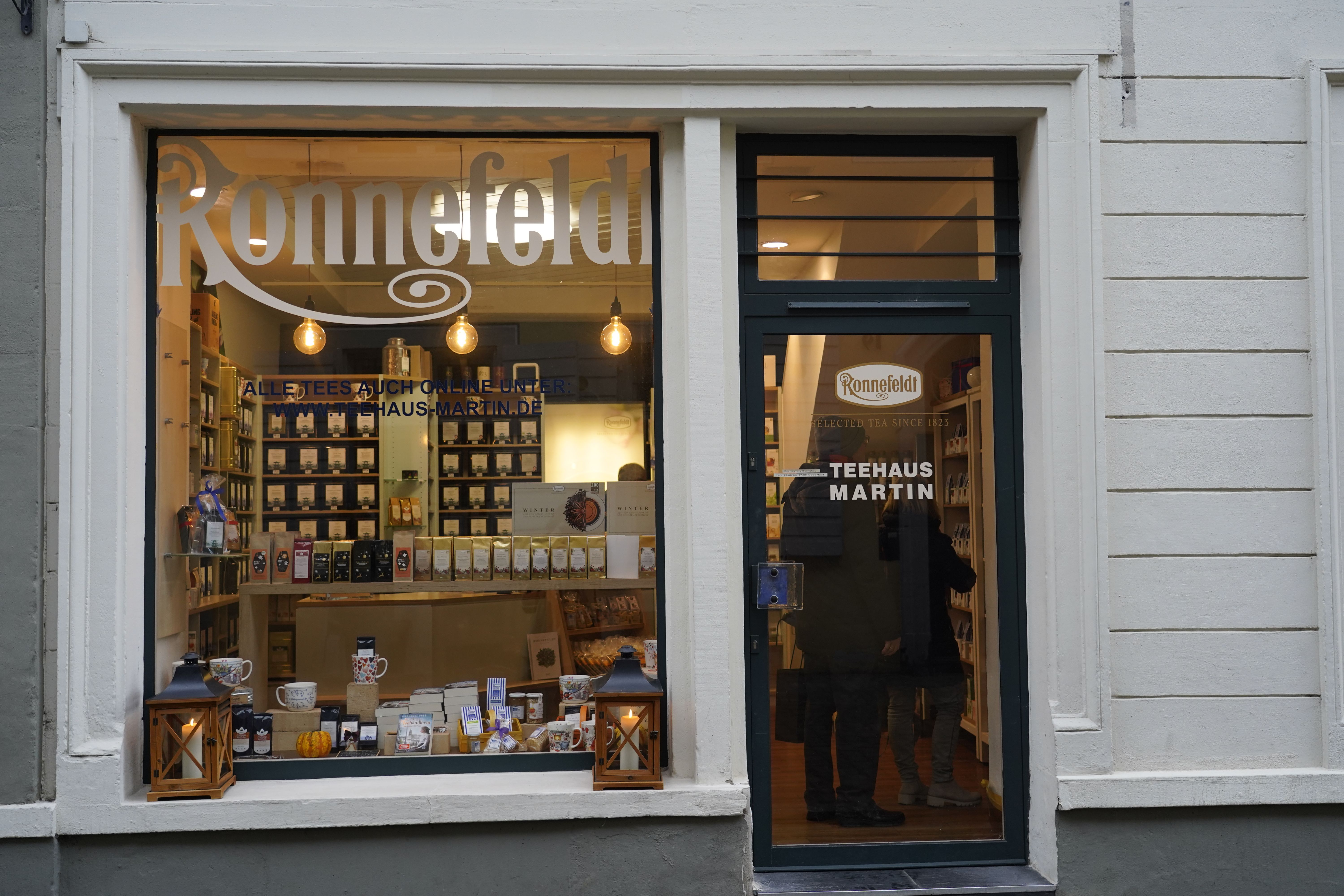 Schaufenster des Teehaus Martin in Freiburg mit Teesorten und Dekoration. Die Tür zeigt das Logo von Ronnefeldt und den Schriftzug 'Teehaus Martin'.