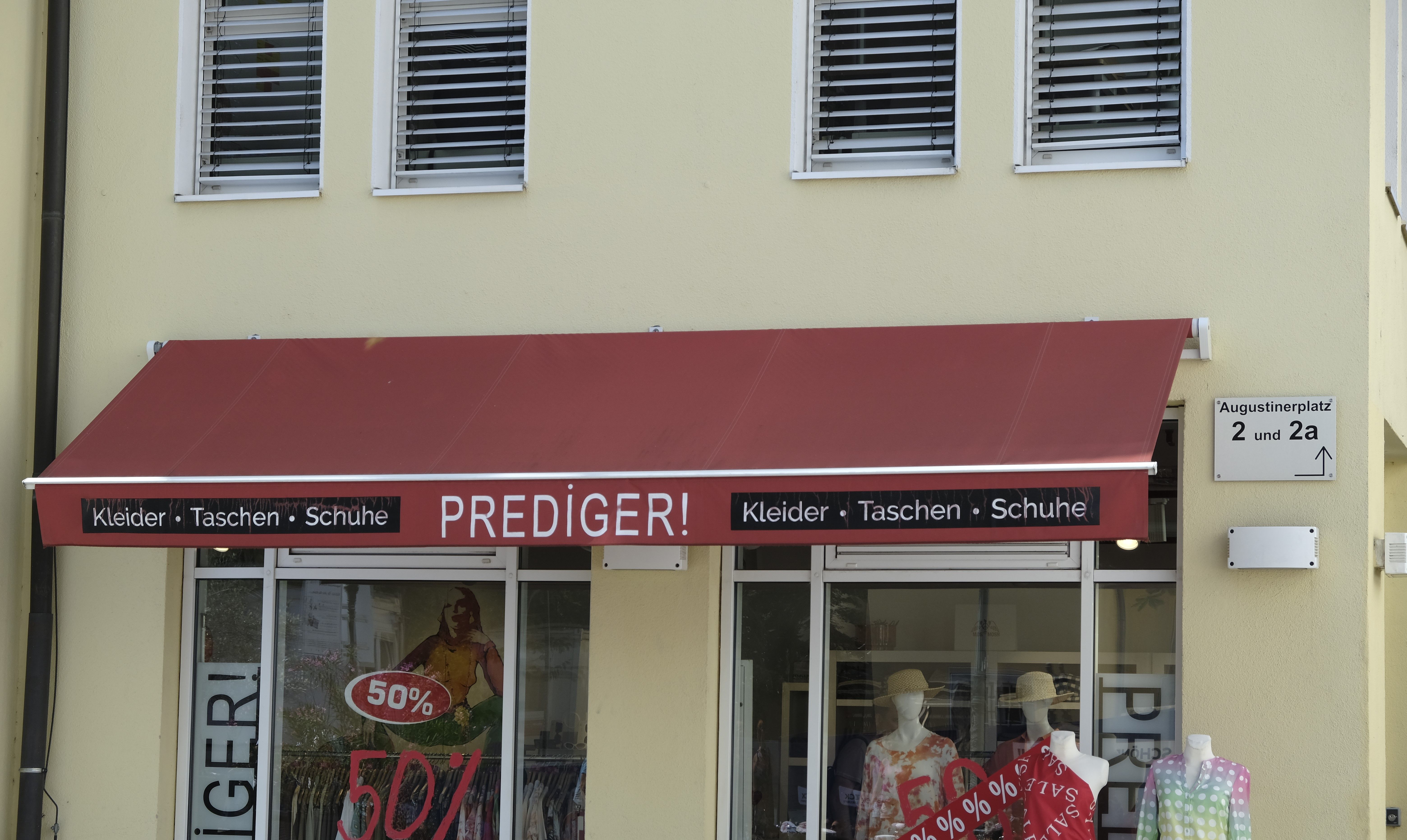 Eingang eines Bekleidungsgeschäfts namens "Prediger" mit rotem Vordach. 