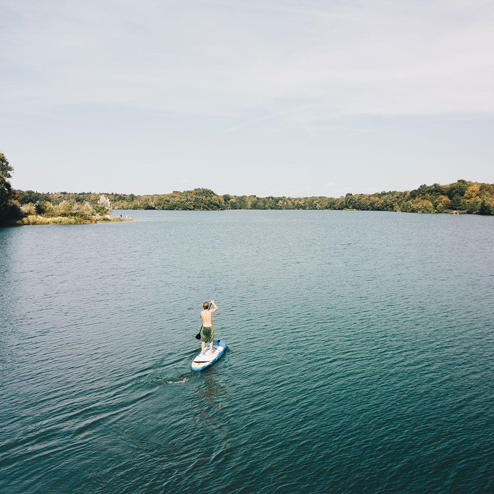Freiburg Opfinger See Stand Up Paddler auf seinem Stand-Up Paddelboard