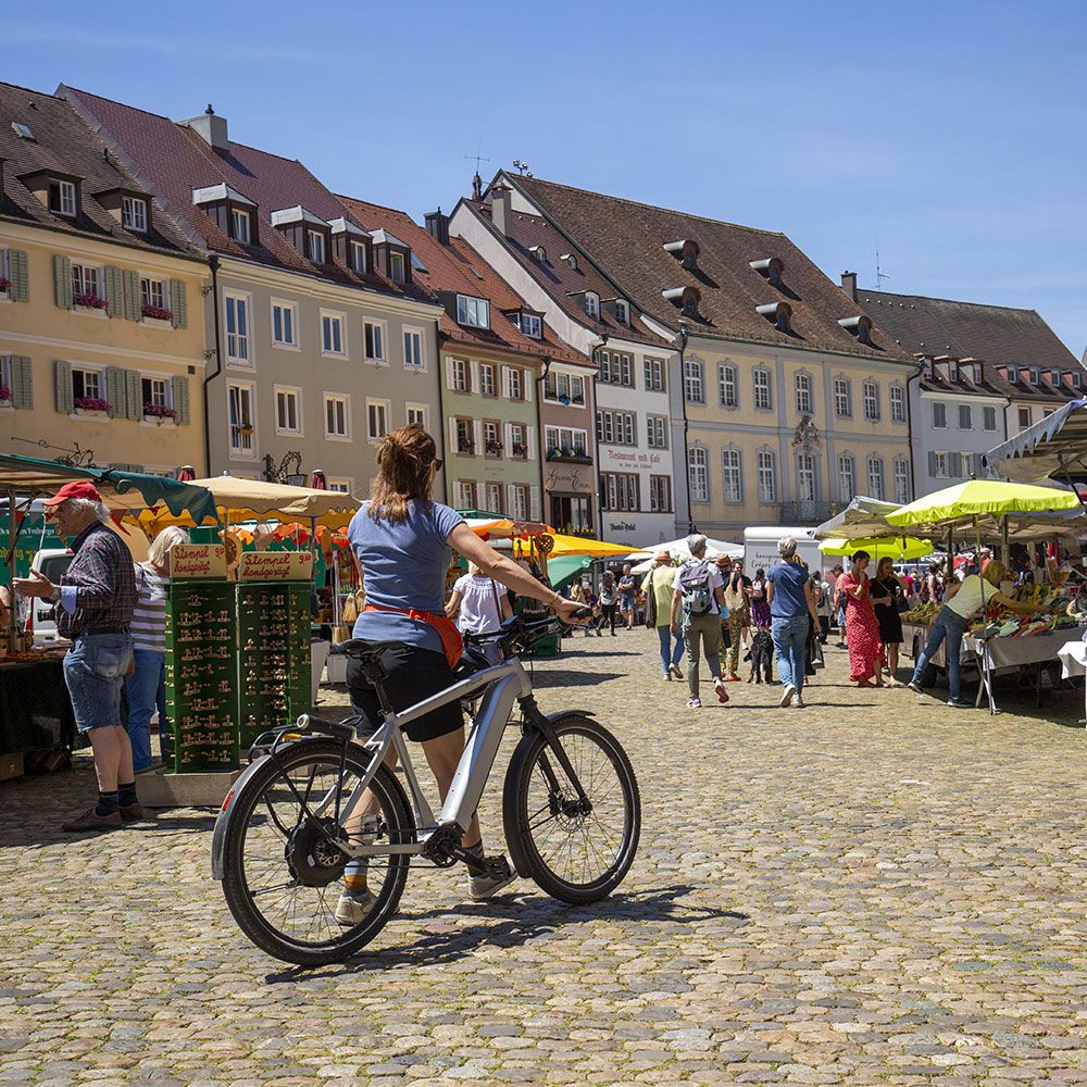 Frau schiebt ein E-Bike auf dem Münsterplatz Freiburg