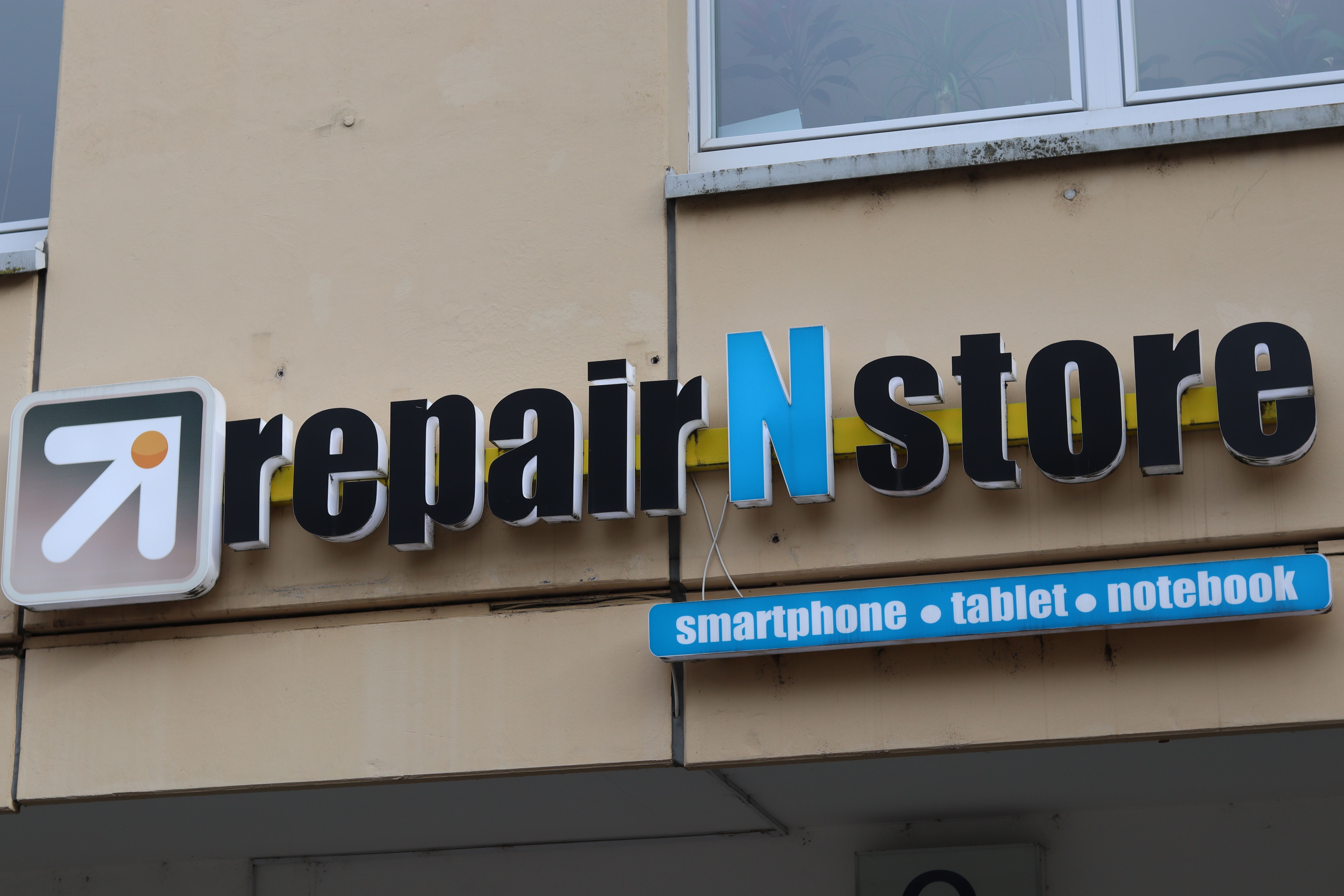 Geschäftsschild von repair N store in Freiburg. Angeboten werden Reparaturen für Smartphones, Tablets und Notebooks.