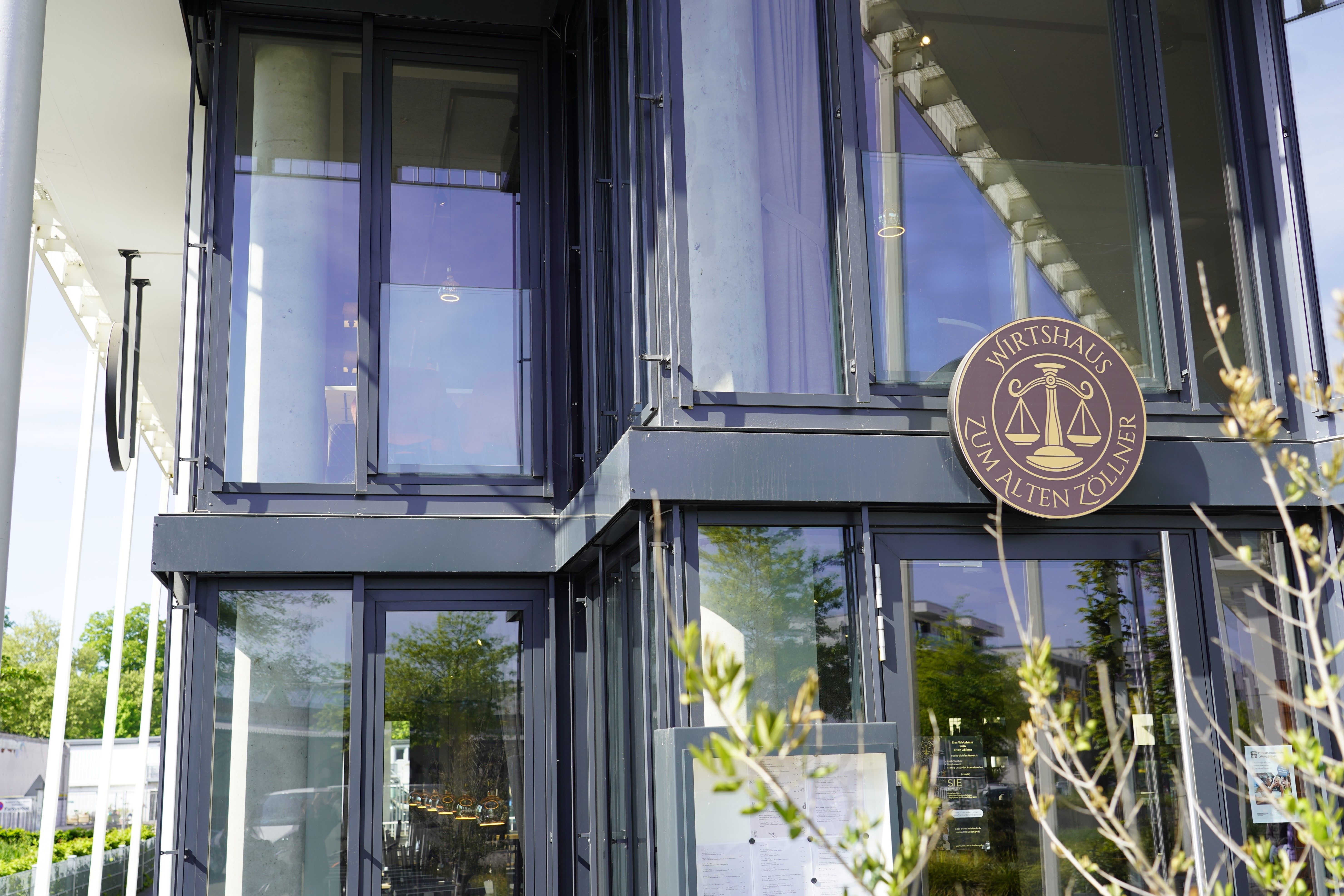 Modernes Gebäude mit Glasfassade und dem Schild 'Wirtshaus zum alten Zöllner' an der Wand.