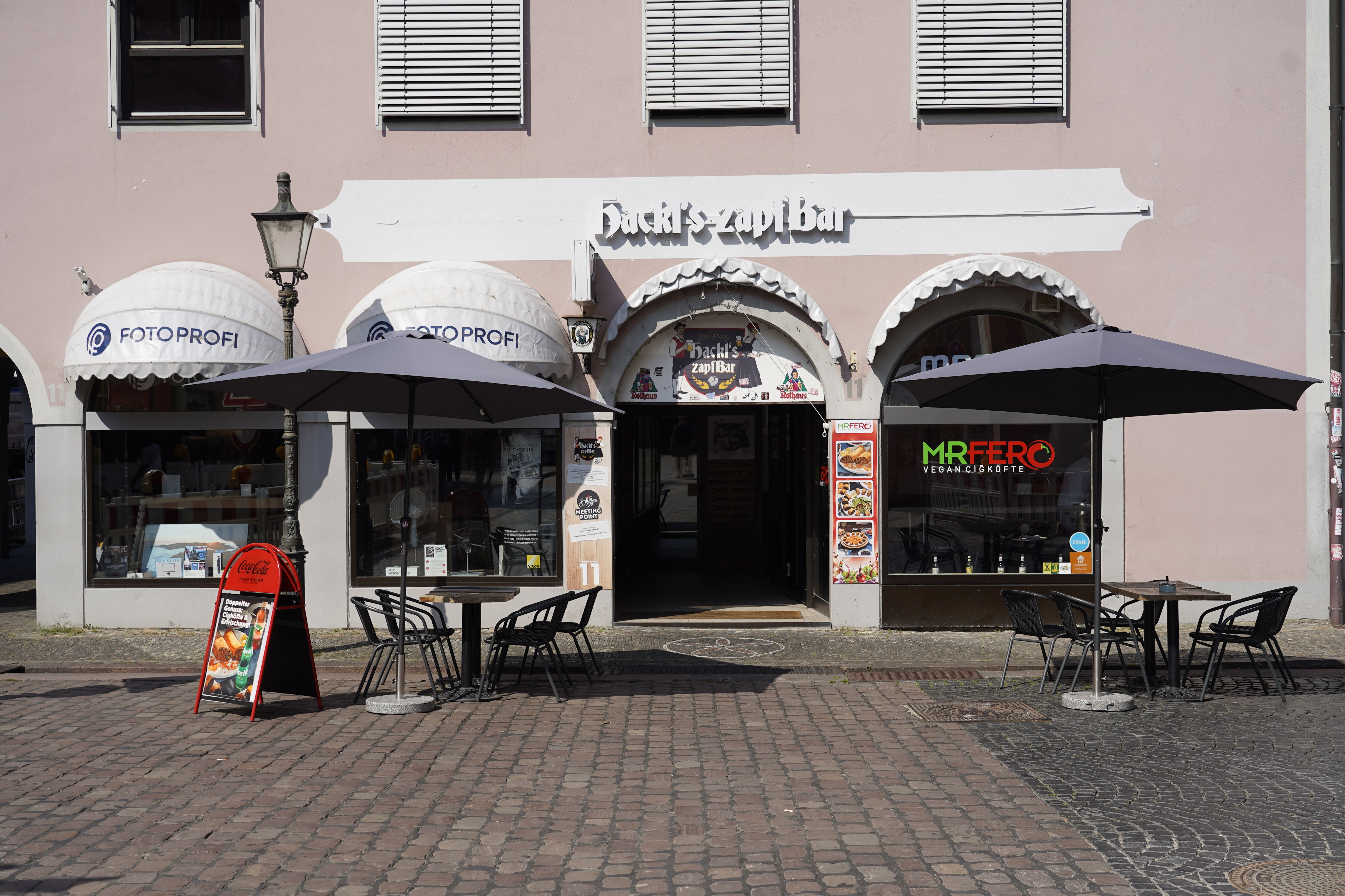 Hackl's Zapfbar mit Außentischen und Sonnenschirmen.