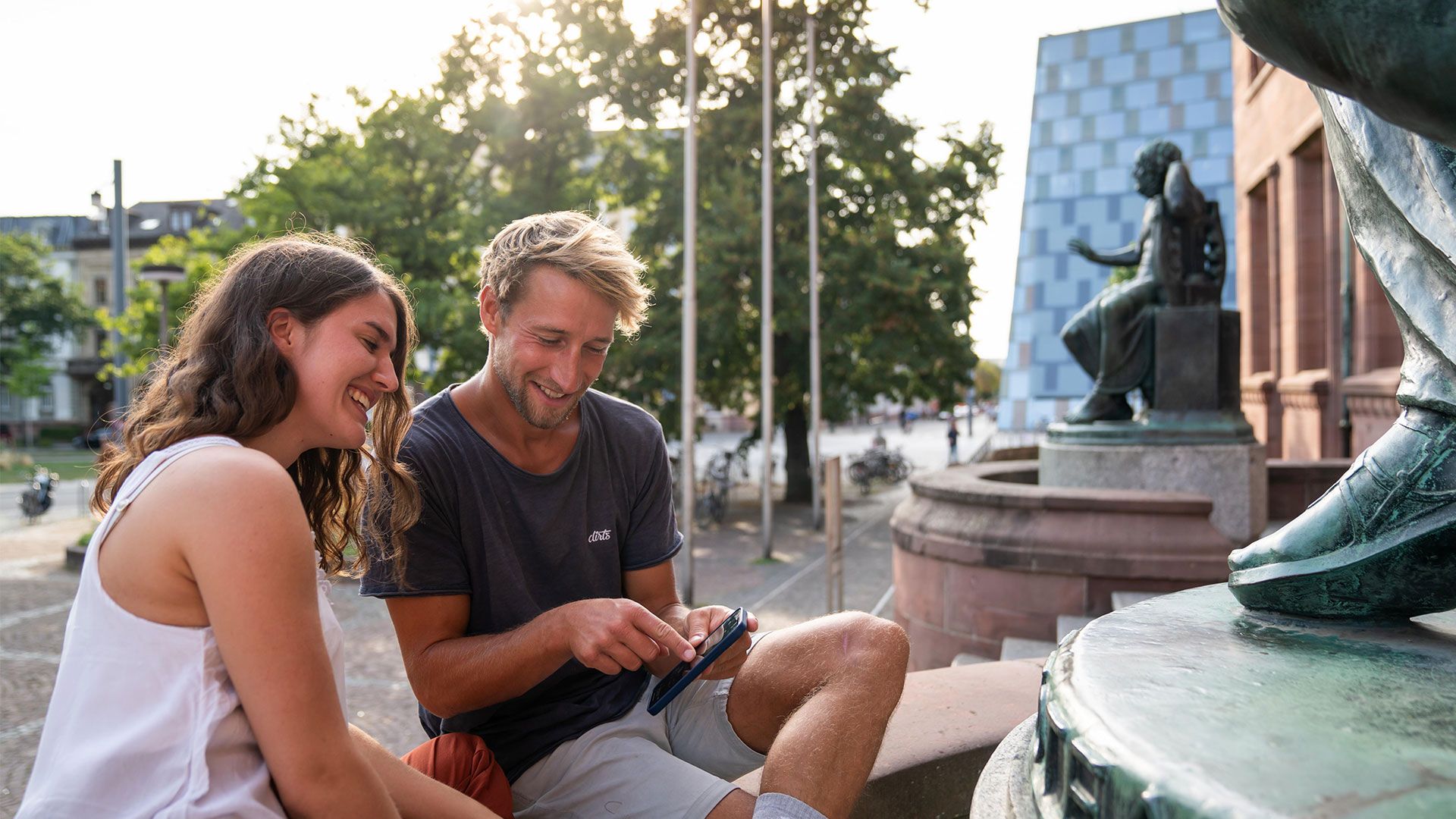 Pärchen in Freiburg vor der Uni Bibliothek schaut auf sein Handy