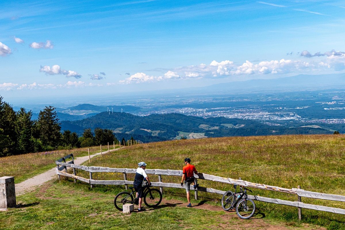 Zwei Mountainbiker an einem Zaun mit Blick ins Tal