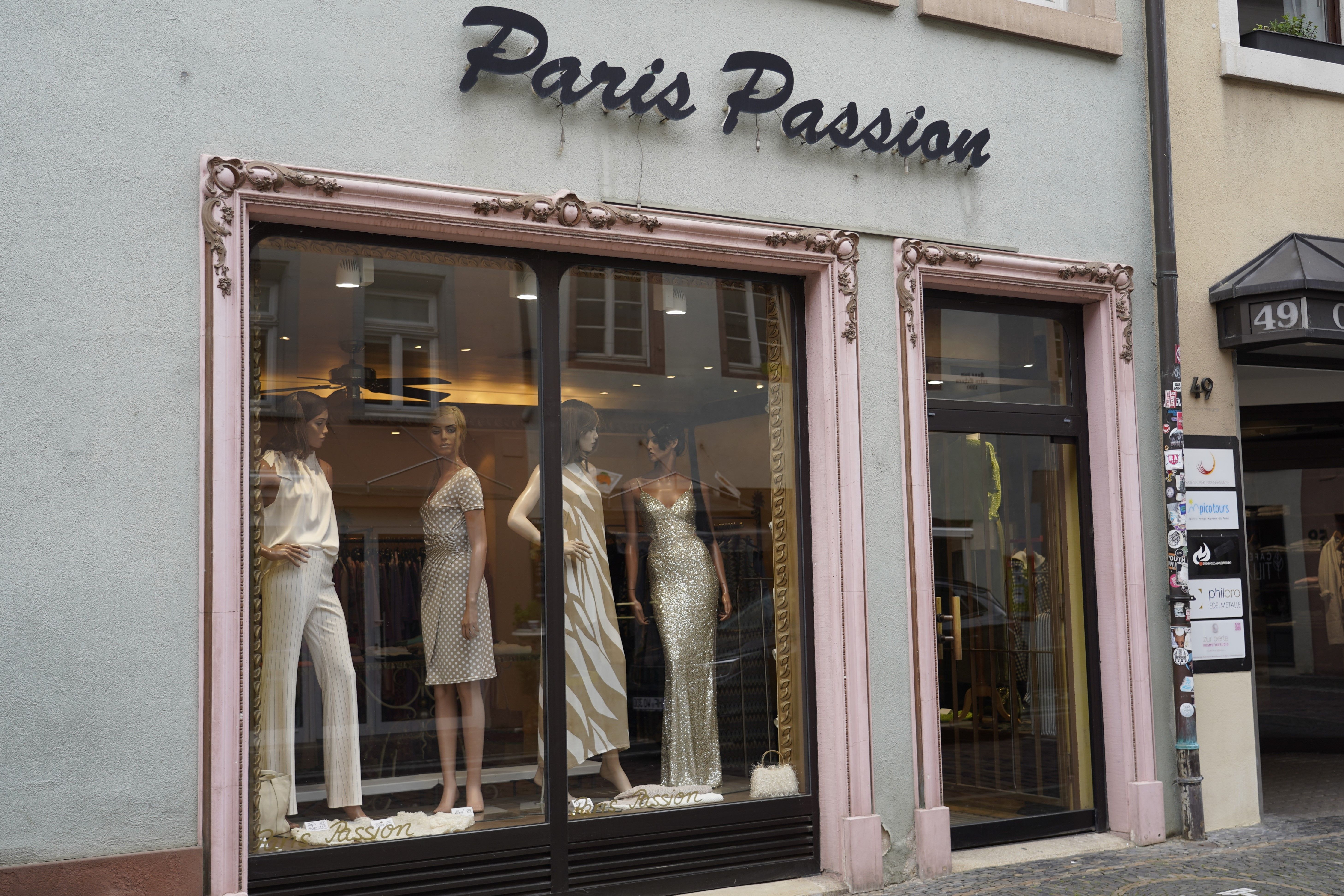 Schaufenster des Modegeschäfts 'Paris Passion' mit Schaufensterpuppen in eleganter Kleidung. Der Laden hat eine dekorative Fassade.