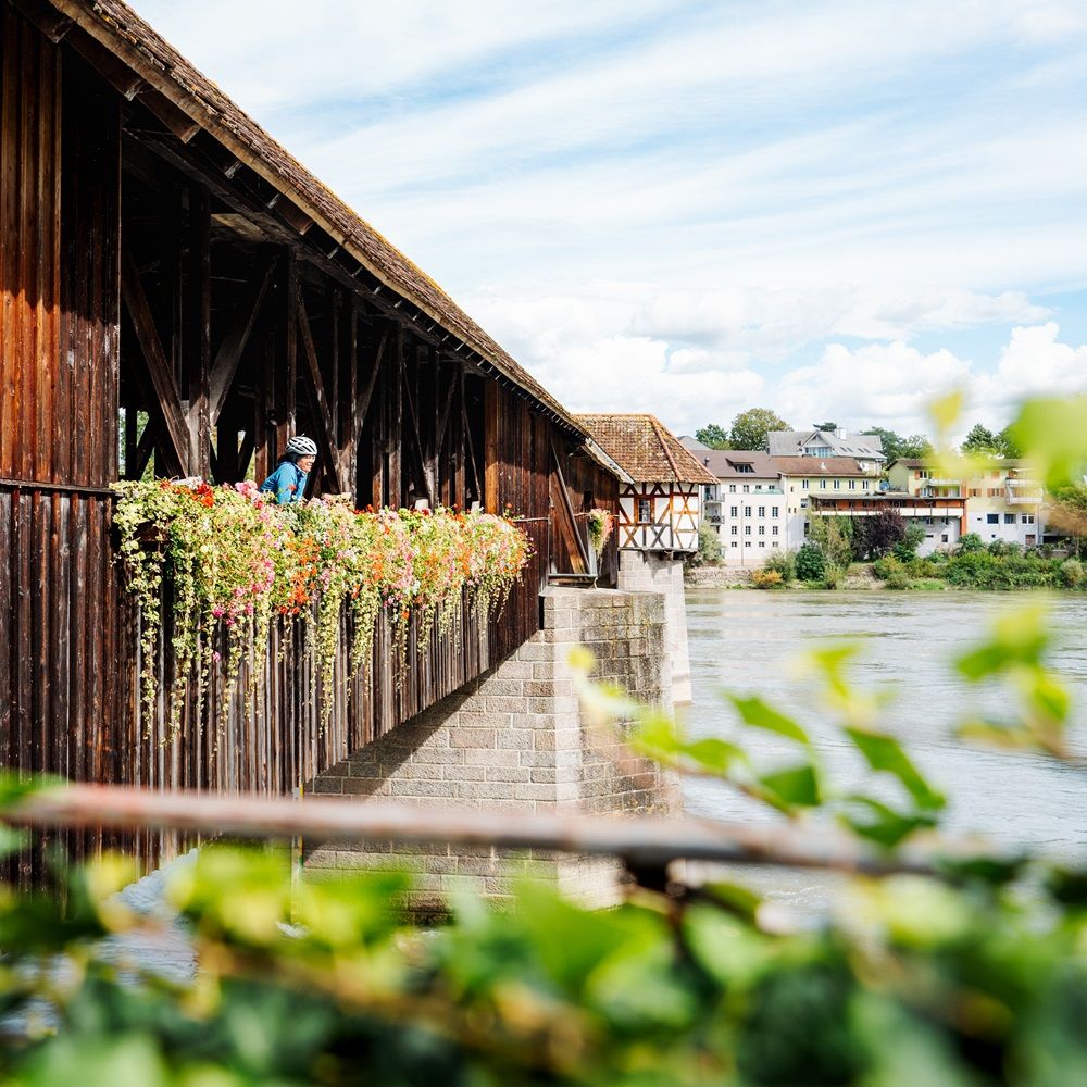 Blick auf die Holzbrücke mit einer Fahrradfahrerin darauf