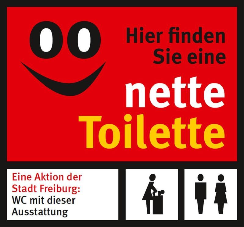 Schild mit lächelndem Gesicht und Text: "Hier finden Sie eine nette Toilette". Unten Symbole für Wickeltisch und WC, Aktion der Stadt Freiburg.