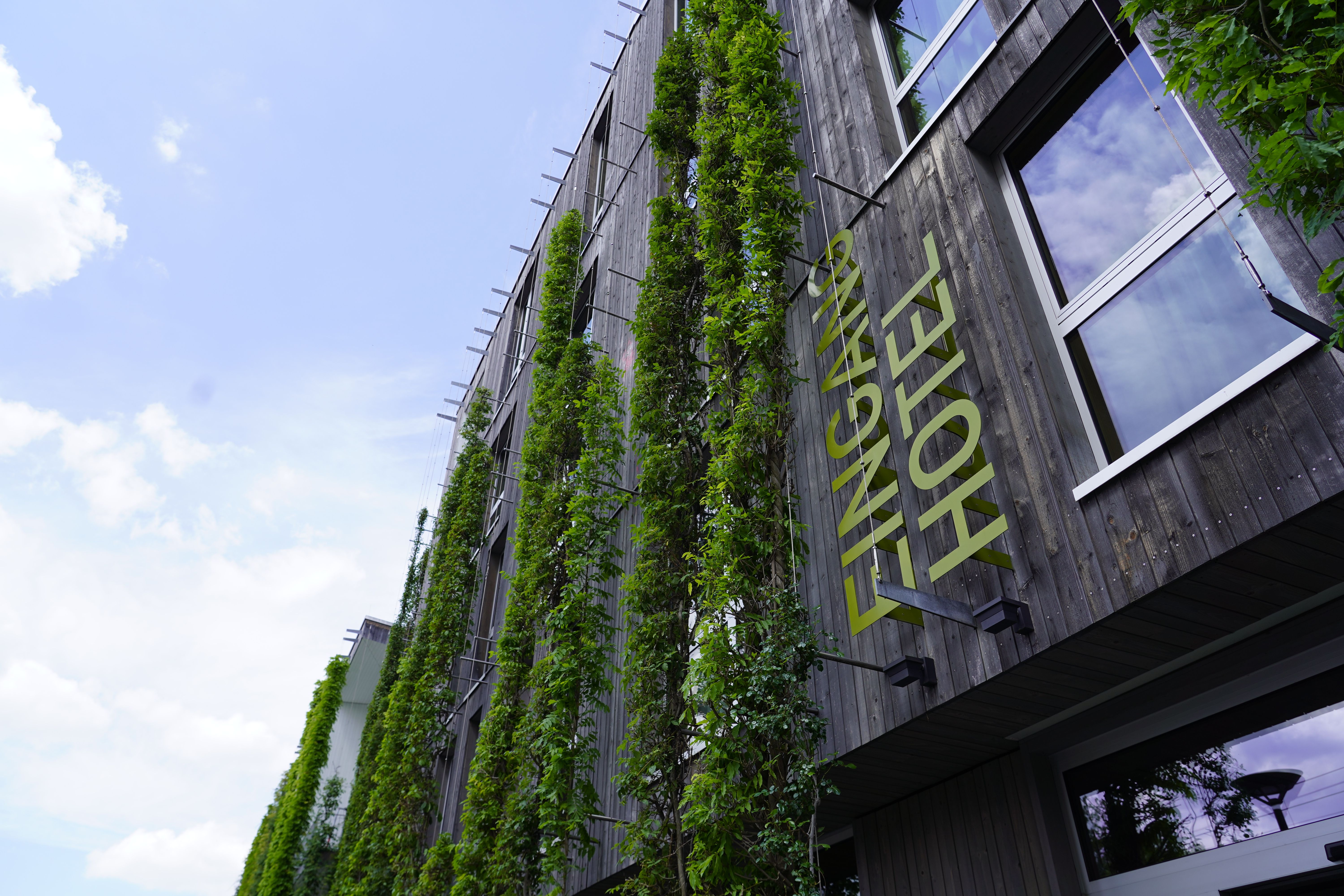 Moderne Hotel-Fassade mit vertikaler Begrünung und großen Fenstern unter blauem Himmel.