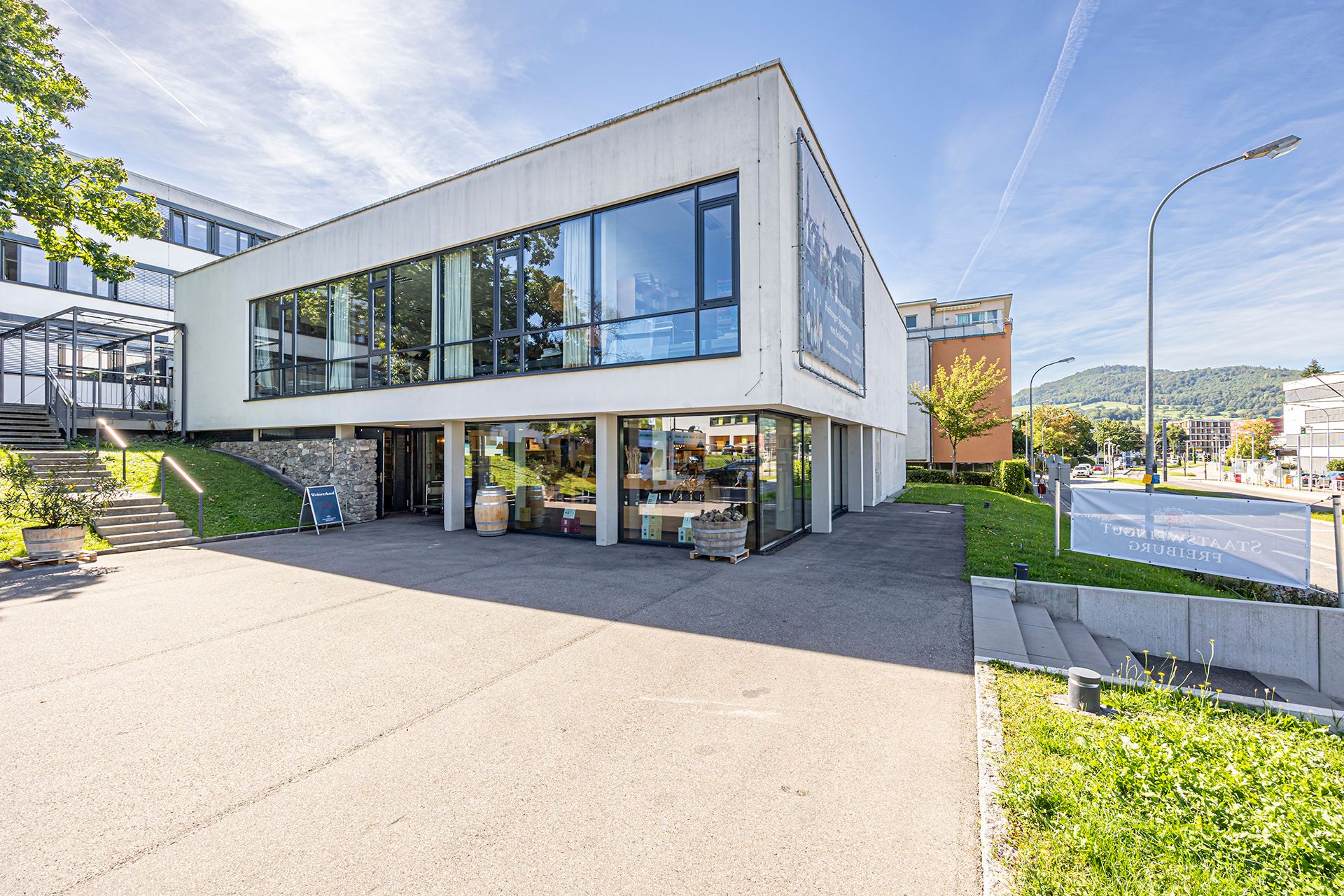 Gebäude des Staatsweinguts Freiburg mit weißer Fassade und Eingang. 