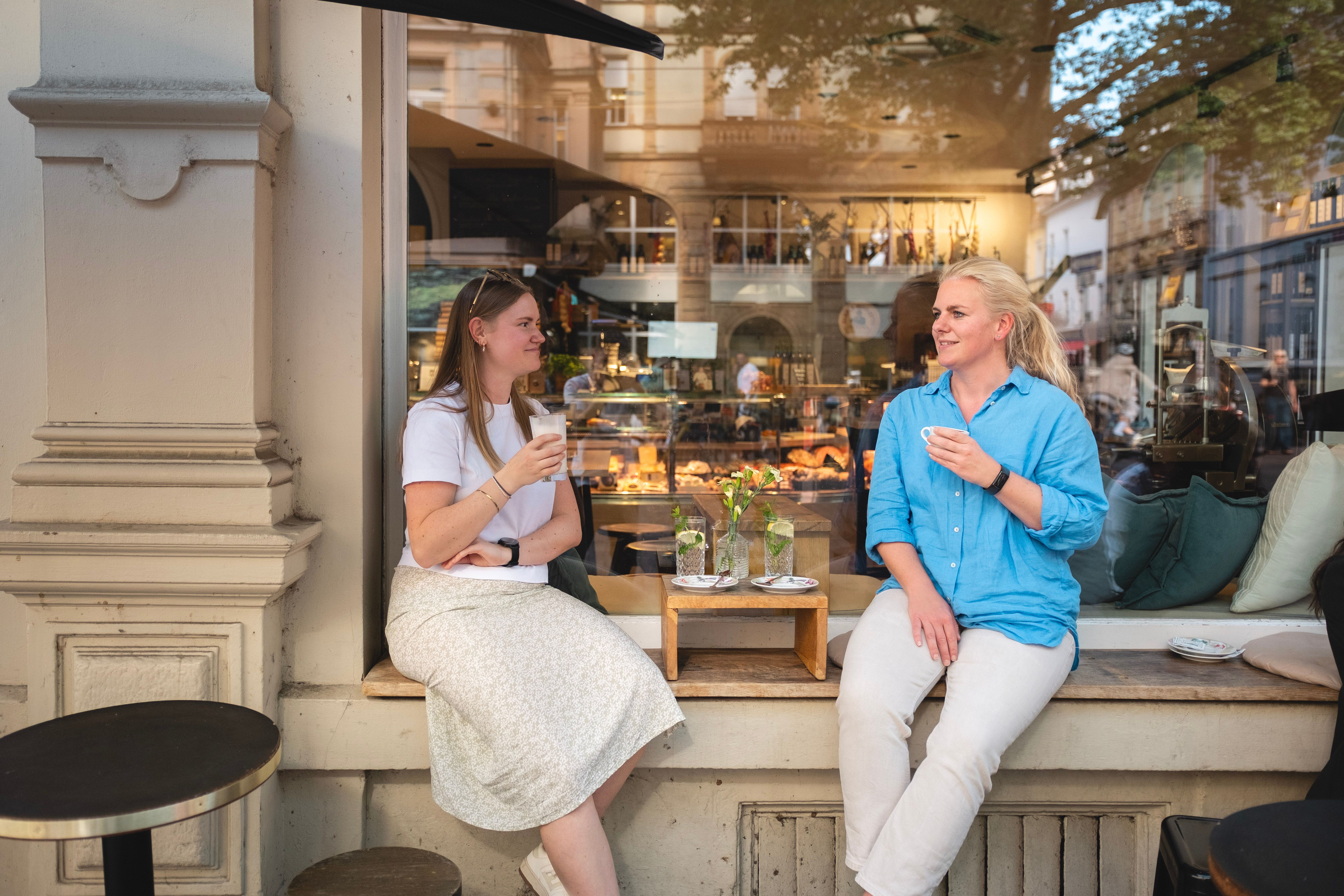 Frauen sitzen im Café-Fenster und trinken Kaffee