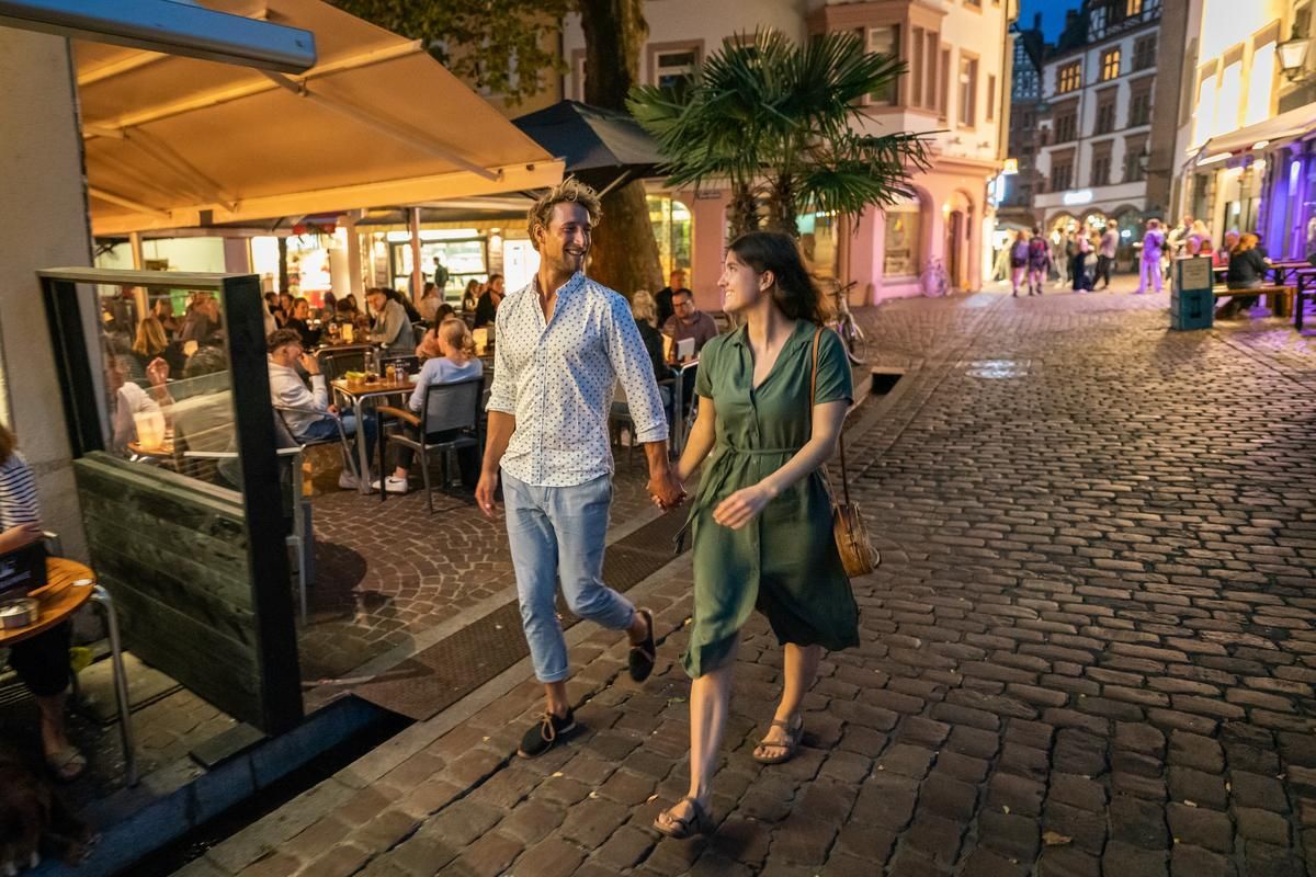 Paar schlendert nachts durch das Kneipenviertel von Freiburg 