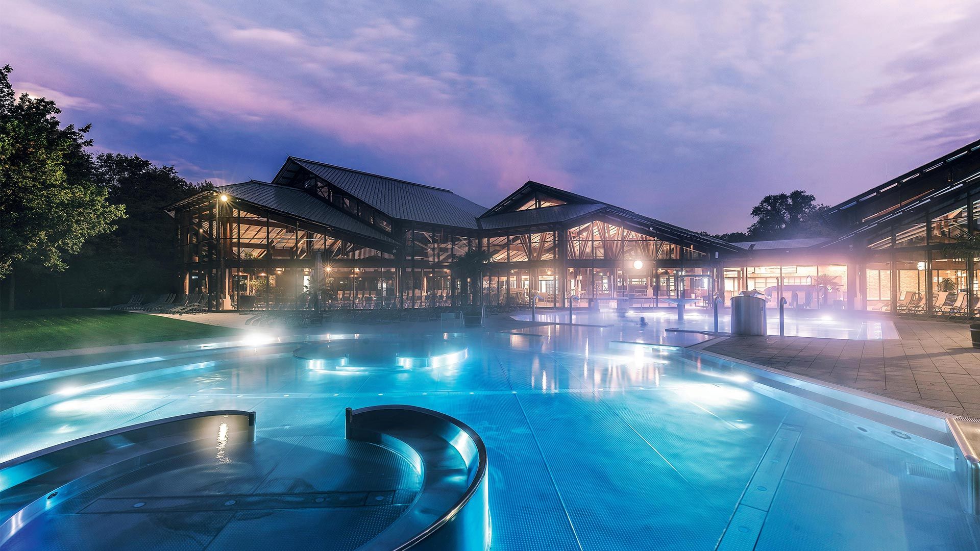 Keidel Therme Freiburg Blick von außen über das Schwimmbecken auf das Gebäude am Abend