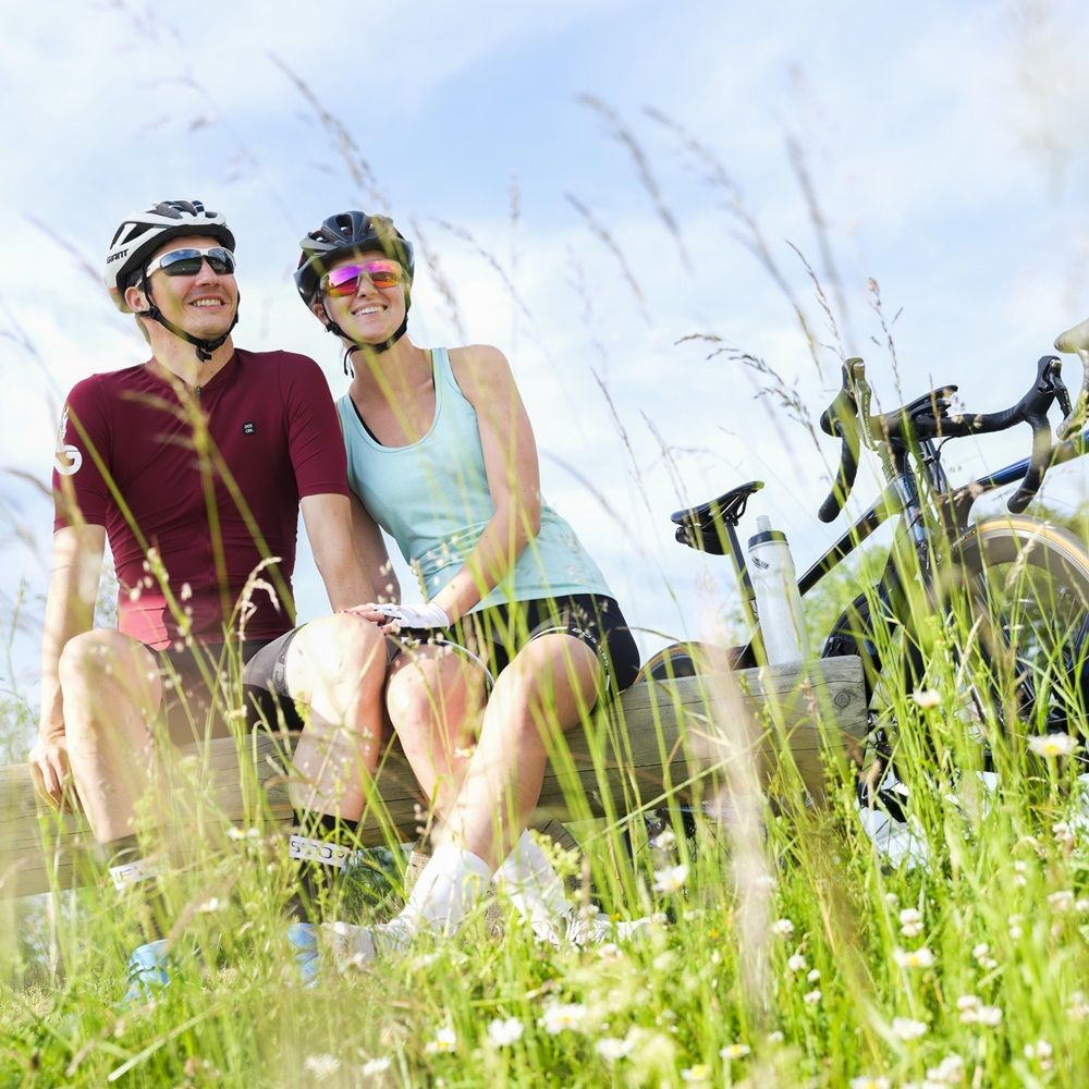Zwei Personen auf einer Parkbank, neben ihnen stehen zwei Rennräder