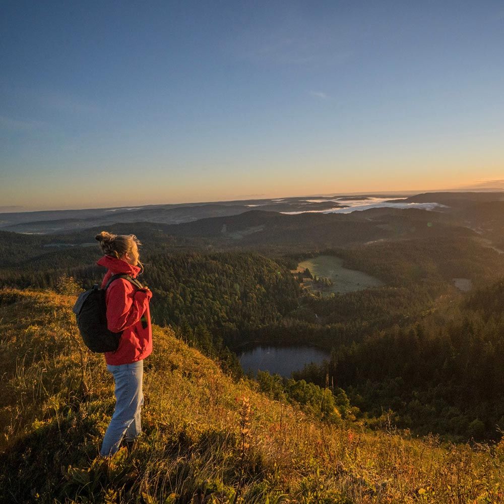 Aussichtspunkt Feldbergsteig Feldberg eine Frau mit roter Jacke schaut in die Weite