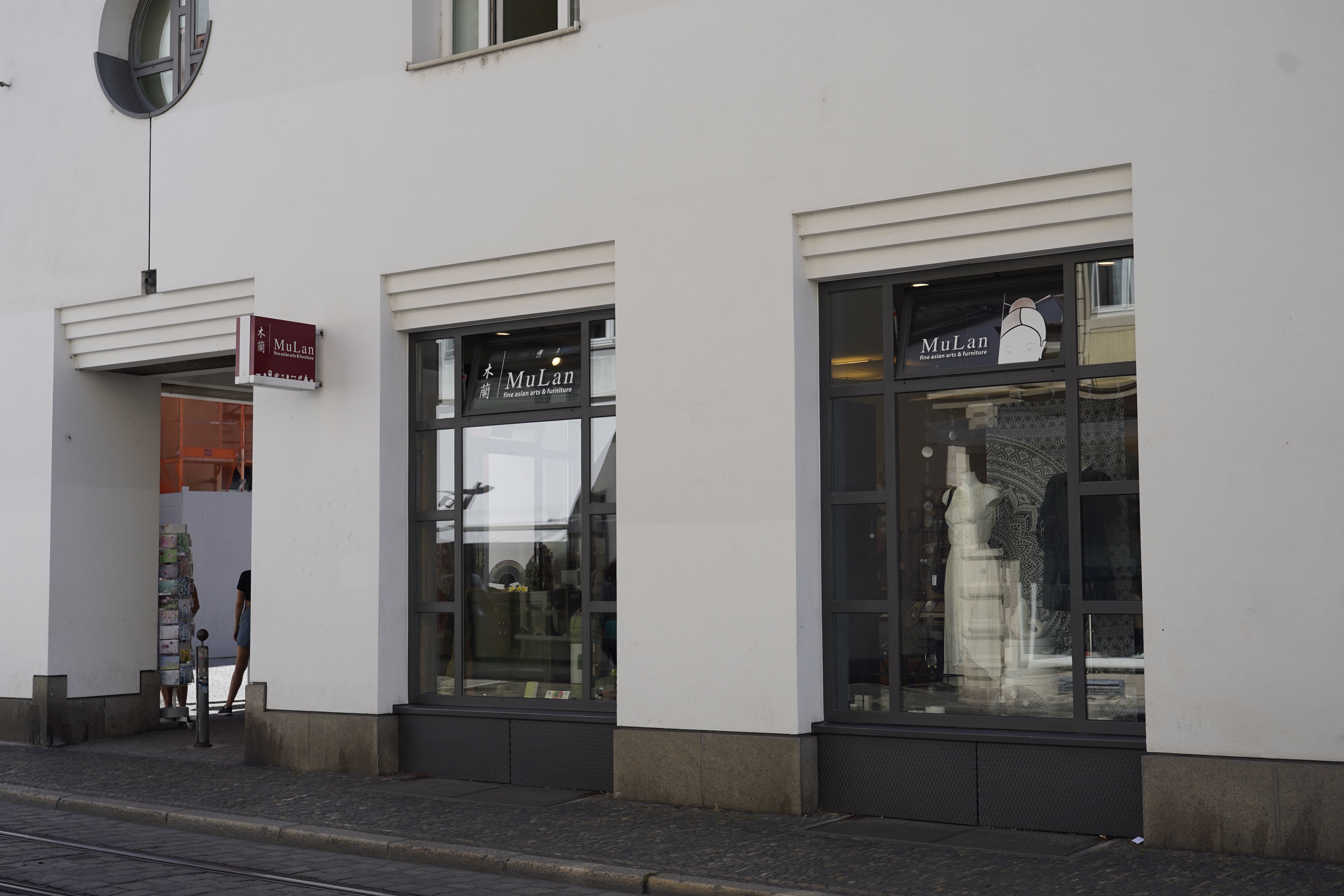 Ein Geschäft namens MuLan in Freiburg mit großen Schaufenstern und einem Schild über dem Eingang.