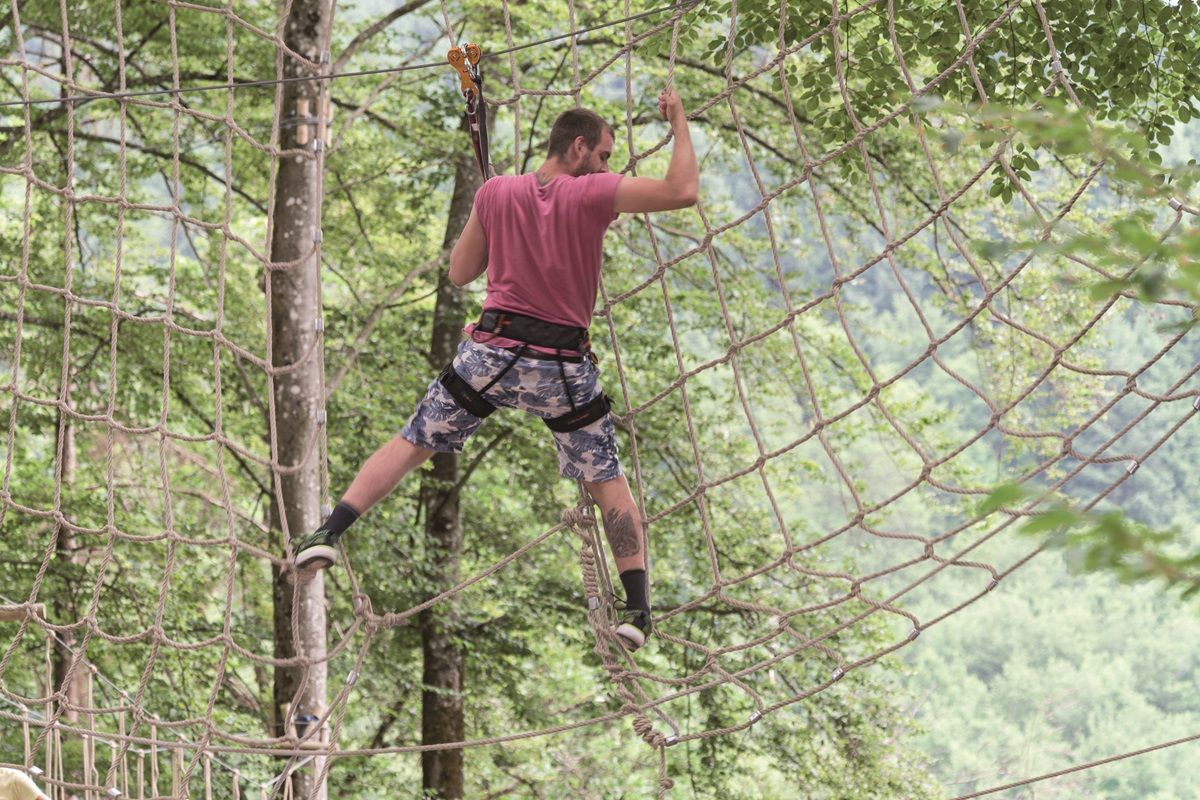 Mann klettert auf den Seilen im Kletterpark