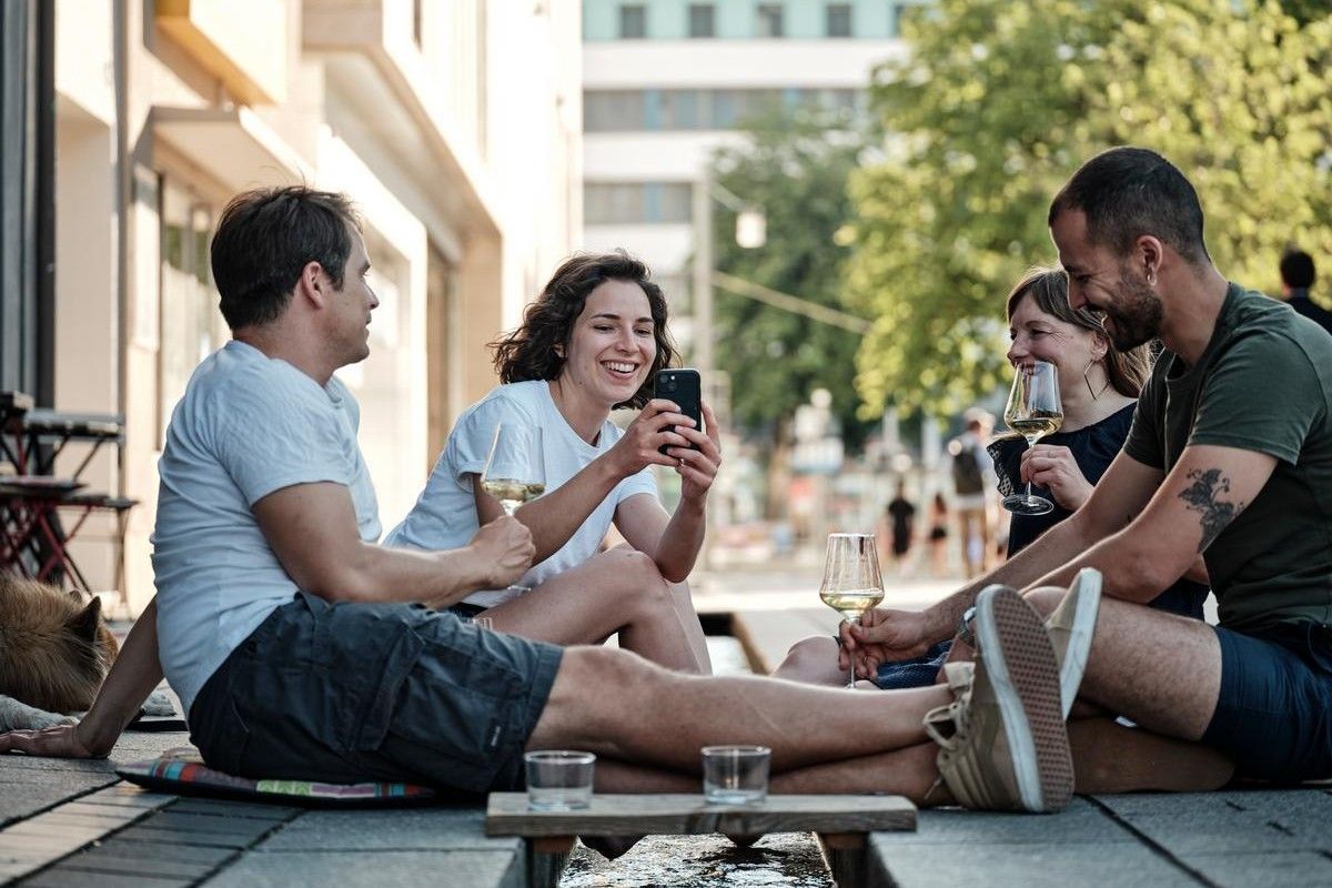 Eine Gruppe junger Menschen sitzt mit Getränken am Bächle